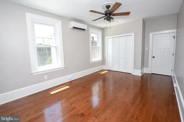 a view of an empty room with window and wooden floor