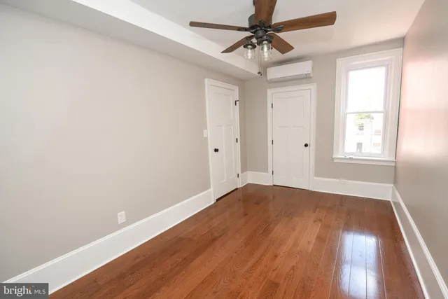an empty room with wooden floor fan and windows