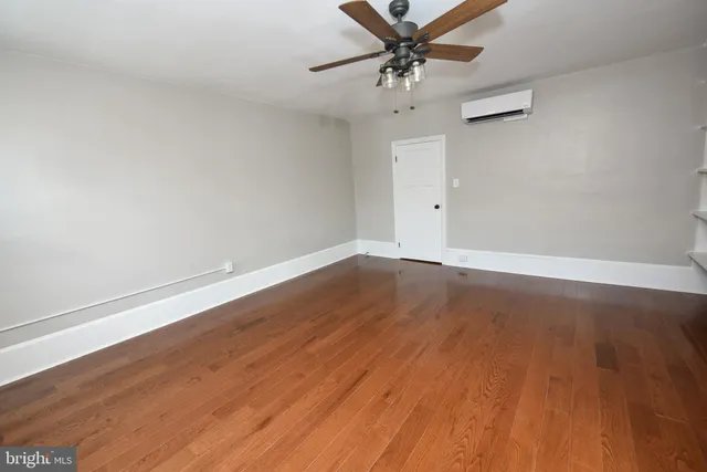an empty room with wooden floor and fan