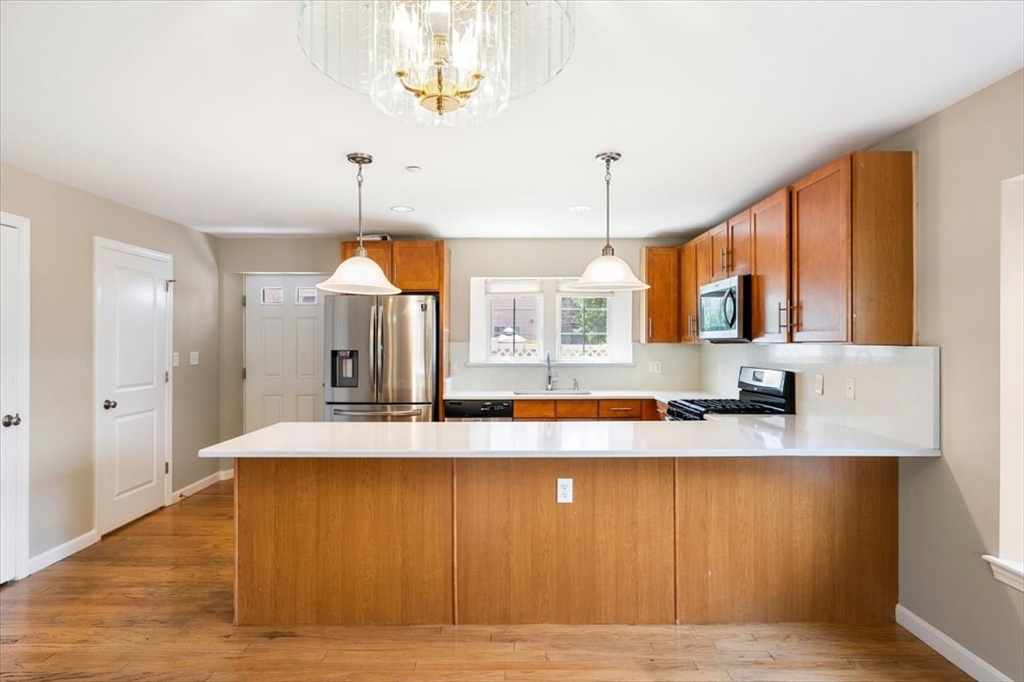 6 Bates Street, Unit A Devens, MA 01434 - Photo 14 of 41 a view of a kitchen with kitchen island a sink wooden floor and a window