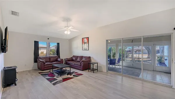 a living room with furniture a flat screen tv and glass door