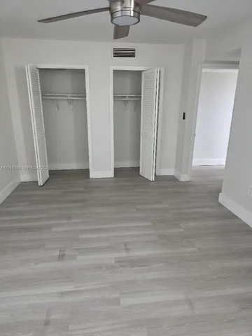 a view of an empty room with wooden floor and closet