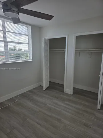 an empty room with wooden floor closet and windows
