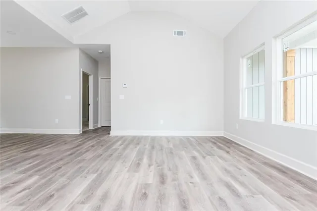 an empty room with wooden floor and windows