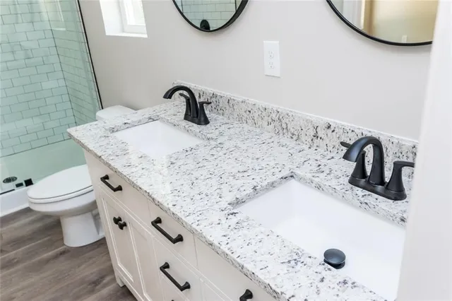 a bathroom with a granite countertop sink and a toilet