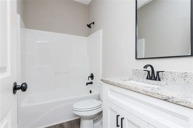 a bathroom with a granite countertop sink a toilet and a bathtub
