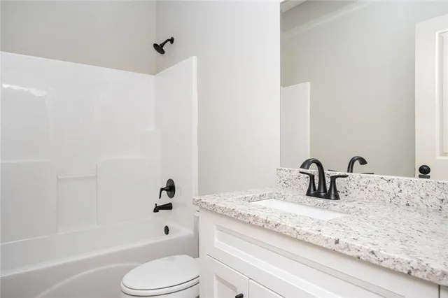 a bathroom with a granite countertop sink toilet and bathtub