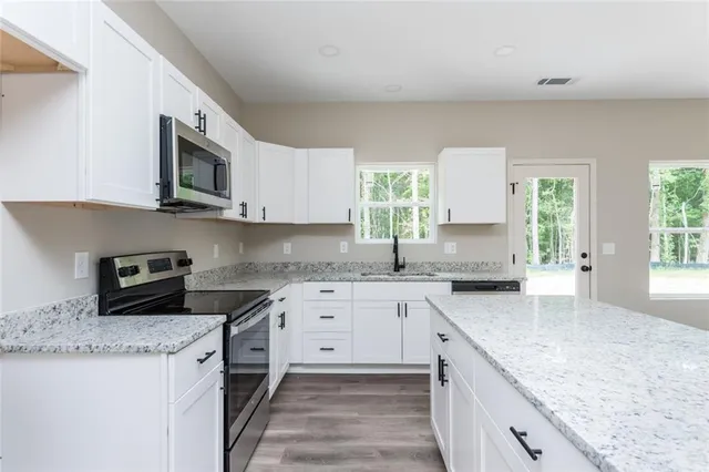 a kitchen with stainless steel appliances granite countertop a sink stove and microwave