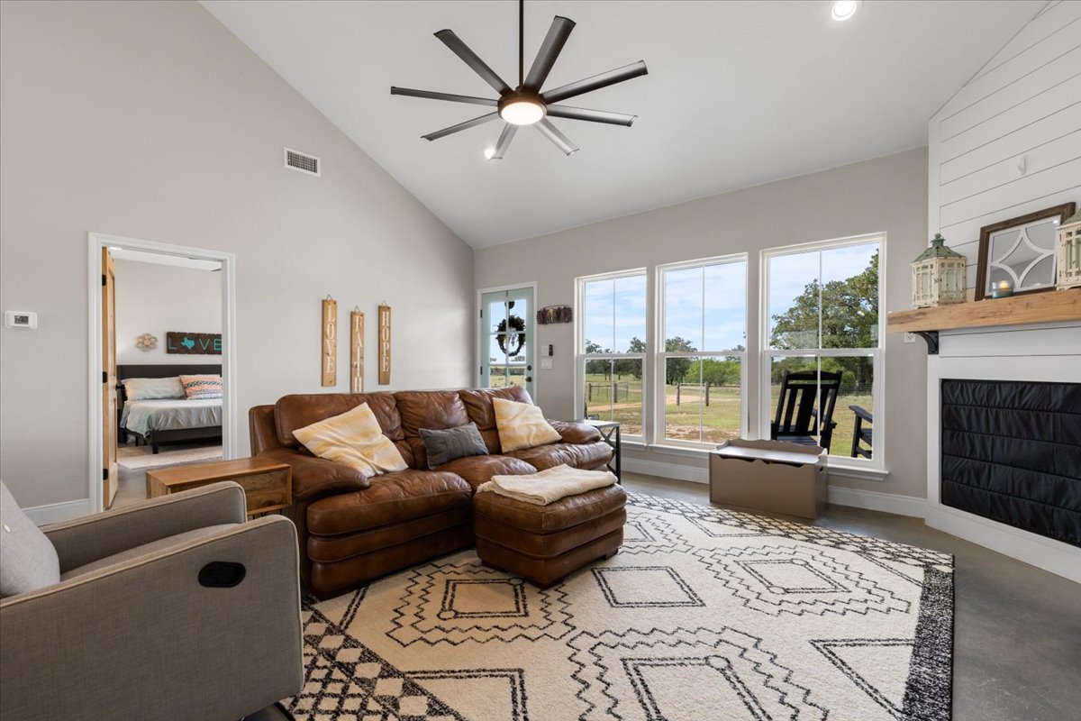 3389 Sparta Field Road Waelder, TX 78959 - Photo 2 of 40 Living room with ceiling fan, high vaulted ceiling, concrete floors, a fireplace, and recessed lighting