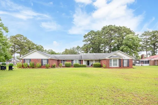 a view of a house with a big yard and large trees
