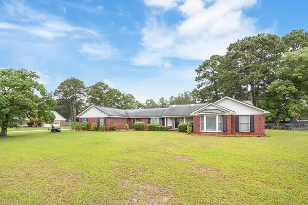 a view of a house with a big yard and large trees