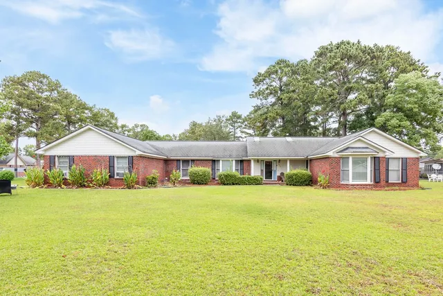 a view of a house with a big yard and large trees