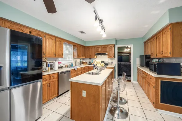 a kitchen with stainless steel appliances granite countertop a refrigerator a sink dishwasher a stove and white countertops with wooden floor