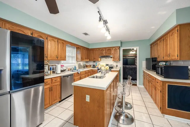 a kitchen with stainless steel appliances granite countertop a refrigerator a sink dishwasher a stove and white countertops with wooden floor