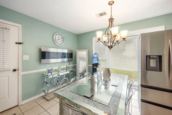 a dining room with wooden floor a chandelier a wooden table and chairs
