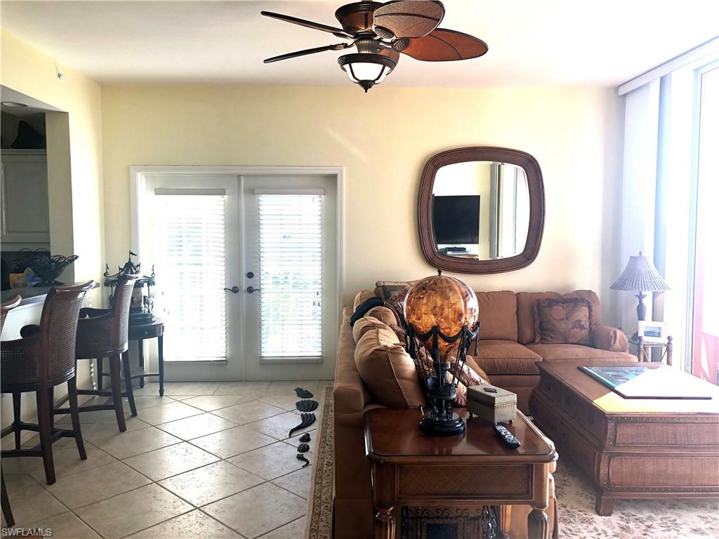 451 Bayfront Place, Unit 5311 Naples, FL 34102 - Photo 9 of 38 a living room with couches a mirror and a dining table with wooden floor