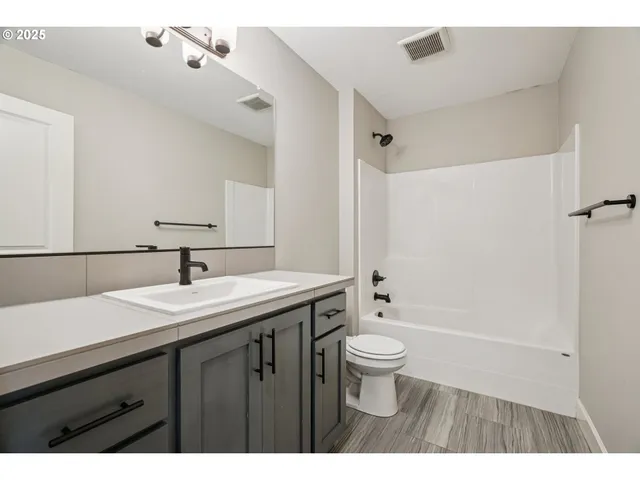 a bathroom with a sink a toilet a large mirror and shower