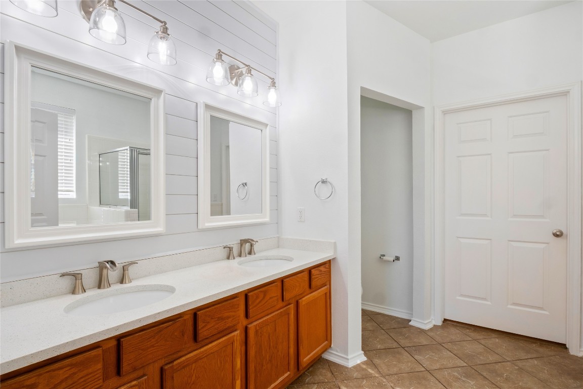 601 Red Hawk Drive Leander, TX 78641 - Photo 20 of 40 Primary bathroom featuring double vanity, a stall shower, and light tile patterned floors