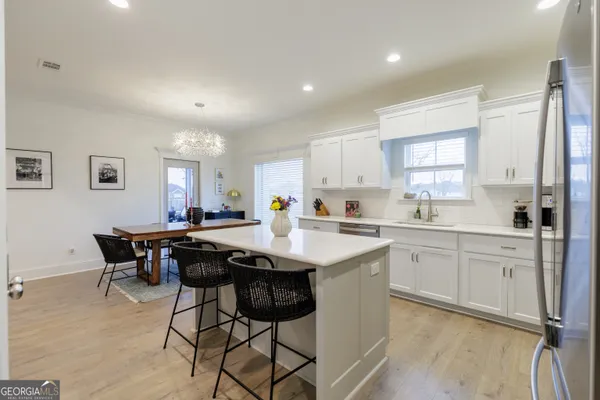a kitchen with stainless steel appliances kitchen island granite countertop a table chairs sink and cabinets