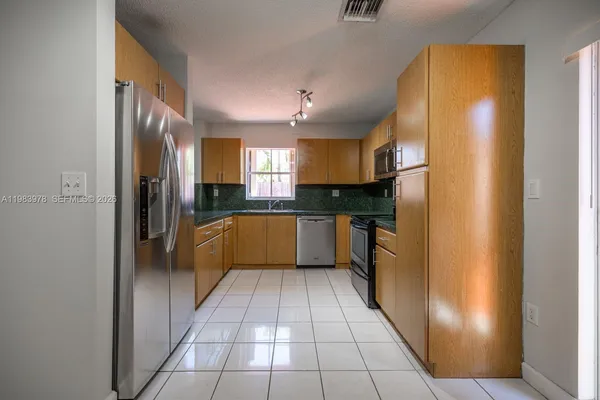 a kitchen with stainless steel appliances granite countertop a refrigerator and a sink