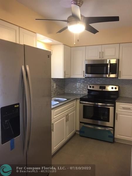 a kitchen with stainless steel appliances kitchen island granite countertop a stove and a refrigerator