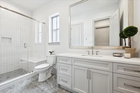 a bathroom with a granite countertop sink a toilet a mirror and shower