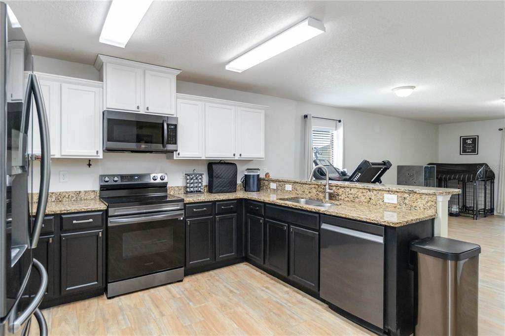 559 Siesta Key Avenue Tavares, FL 32778 - Photo 6 of 24 a kitchen with stainless steel appliances granite countertop a sink stove microwave and refrigerator
