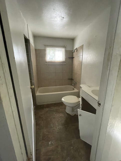 3208 East 16th Street Austin, TX 78721 - Photo 10 of 11 A compact bathroom offers functionality with a tub, toilet, and vanity, ready for personalized updates.