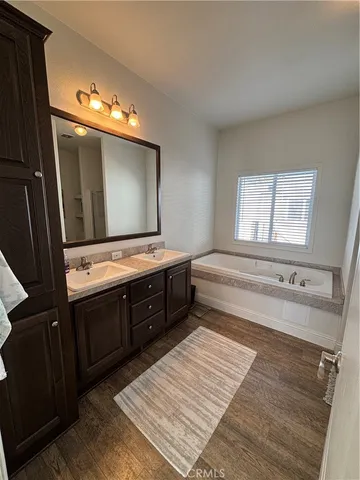 a bathroom with a double vanity sink a mirror and a bathtub