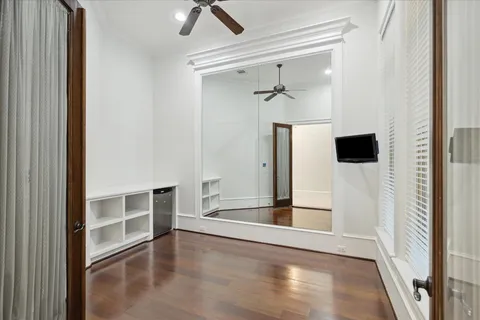 a view of a hallway to a bedroom with wooden floor and cabinet