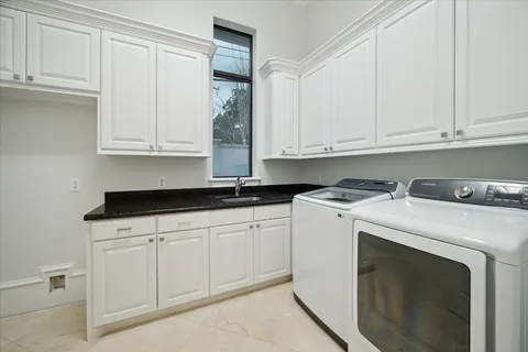 a utility room with stainless steel appliances granite countertop a sink a washer and cabinets
