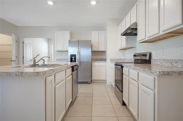 a kitchen with stainless steel appliances granite countertop a sink and a refrigerator