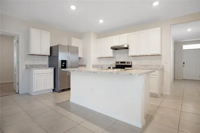 a kitchen with a sink a stove top oven and white cabinets