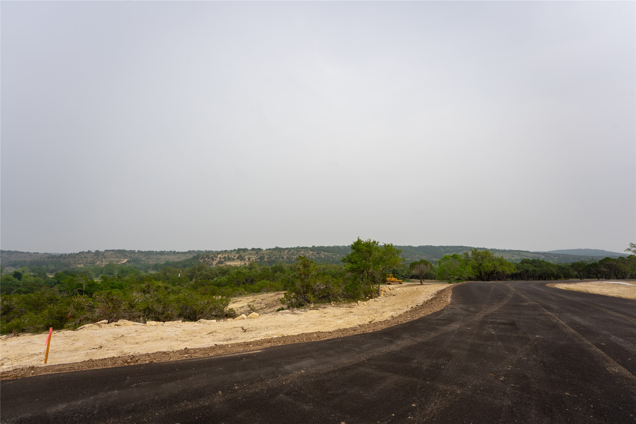 Lot 26 Ranch Road 165 Dripping Springs, TX 78620 - Photo 10 of 13 Paved road extending into a natural landscape with rolling hills and abundant greenery