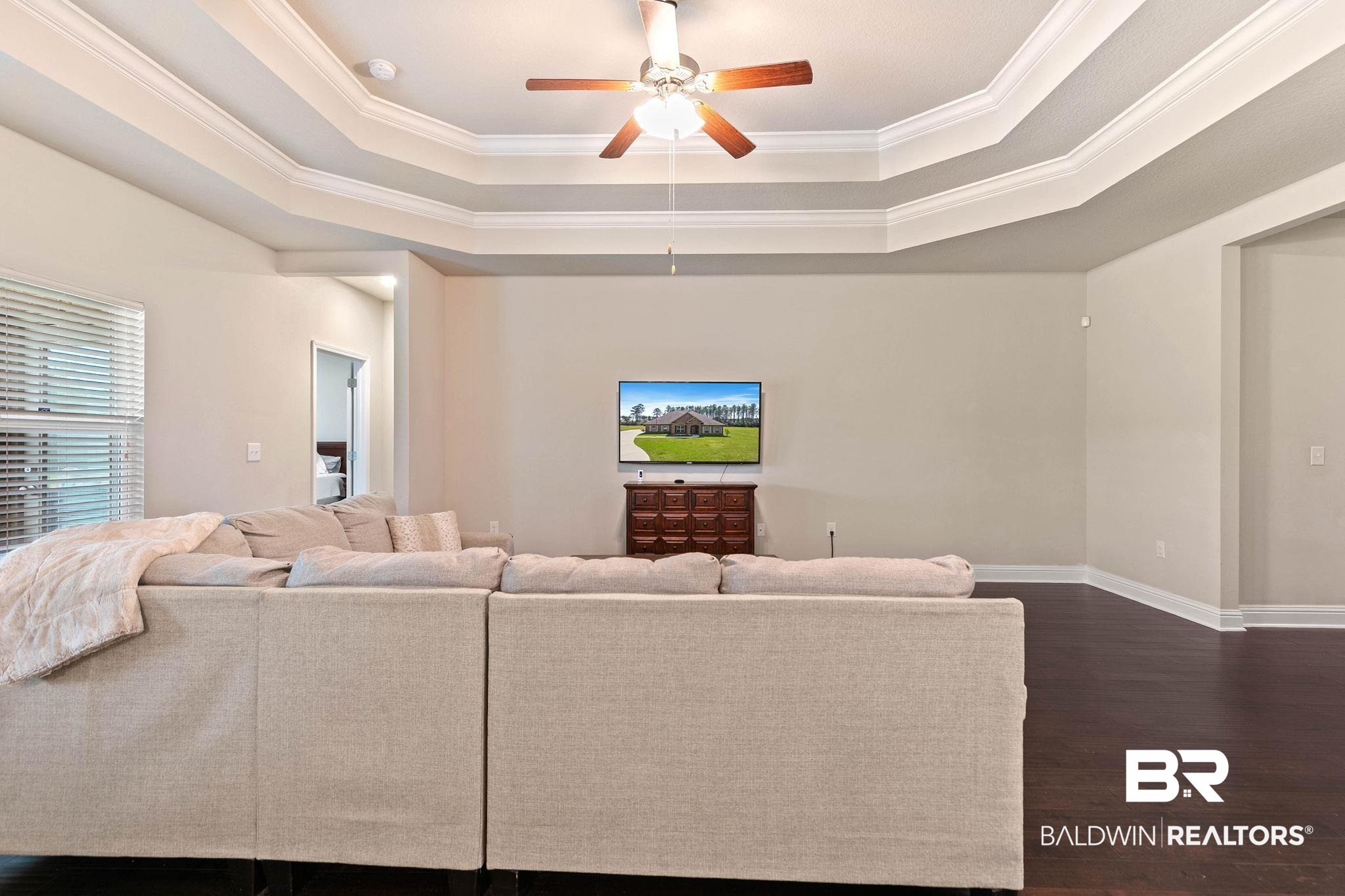 12750 B Jenkins Pit Road Daphne, AL 36527 - Photo 17 of 89 Living room featuring a ceiling fan, dark wood-style flooring, crown molding, and a raised ceiling