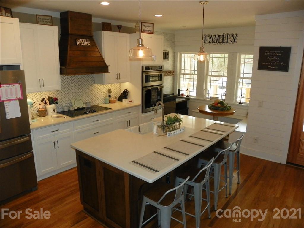 10617 Fink Road Mount Pleasant, NC 28124 - Photo 15 of 45 a kitchen with a sink a stove a refrigerator and a dining table with wooden floor