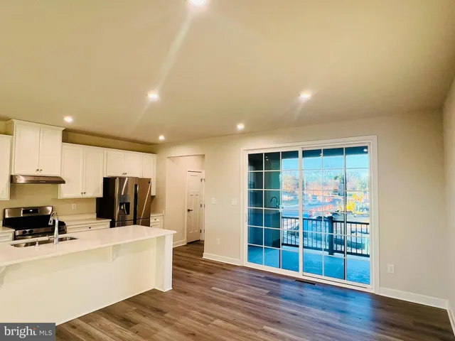 a large white kitchen with wooden floors and a large window