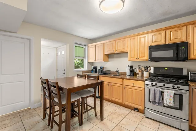 a kitchen with stainless steel appliances a stove a sink dishwasher a microwave oven with a dining table and chairs