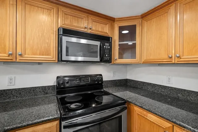 a kitchen with granite countertop wood cabinets and a stove top oven