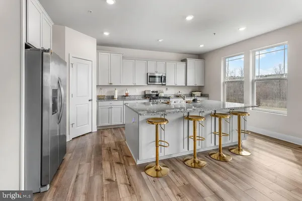 a kitchen with kitchen island granite countertop a sink cabinets and stainless steel appliances