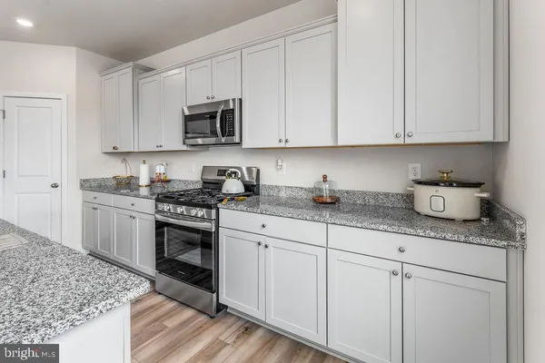 a kitchen with granite countertop white cabinets and stainless steel appliances
