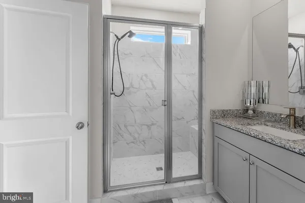 a bathroom with a granite countertop sink a mirror and a shower