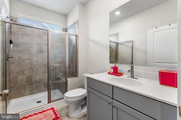 a bathroom with a shower sink vanity mirror and toilet