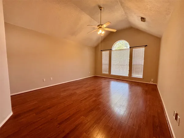 an empty room with wooden floor fan and window
