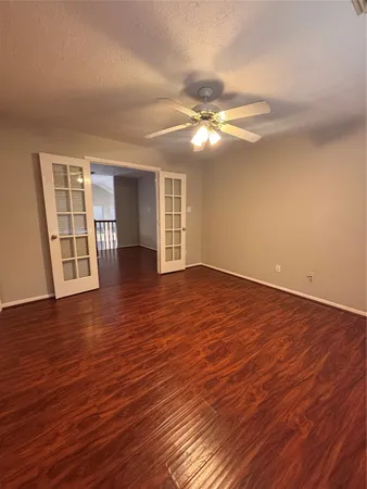 a view of empty room with wooden floor and fan