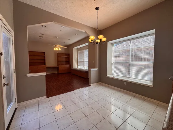 a view of an empty room with a window and a kitchen