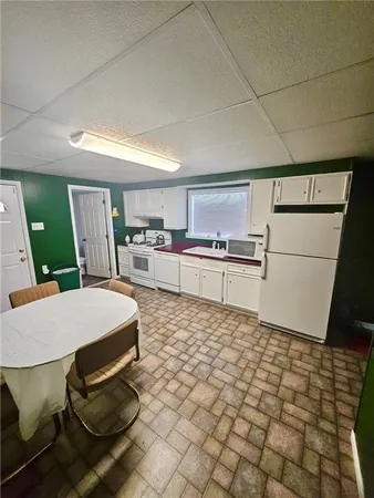a large kitchen with kitchen island a stove a table chairs and a refrigerator