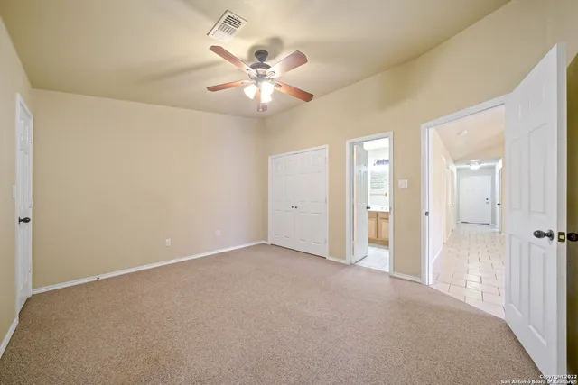 a view of an empty room and chandelier fan