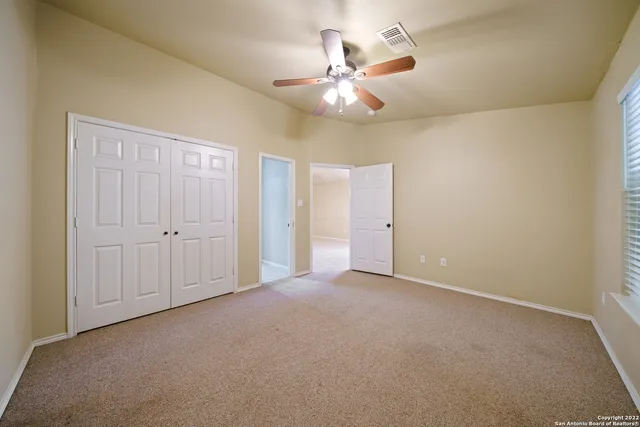 an empty room with a chandelier fan and closet area