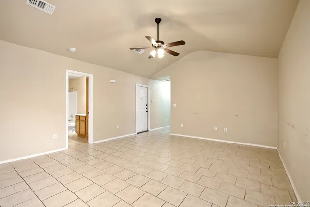 a view of an empty room and chandelier fan